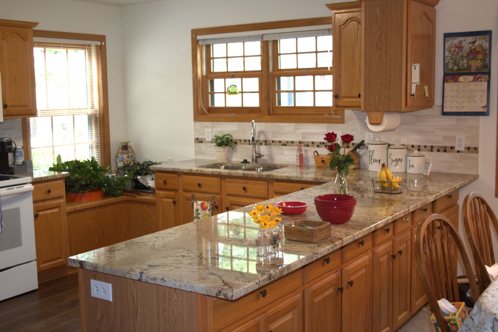 Kitchen with light wood cabinets, granite countertops, and a sunny window.