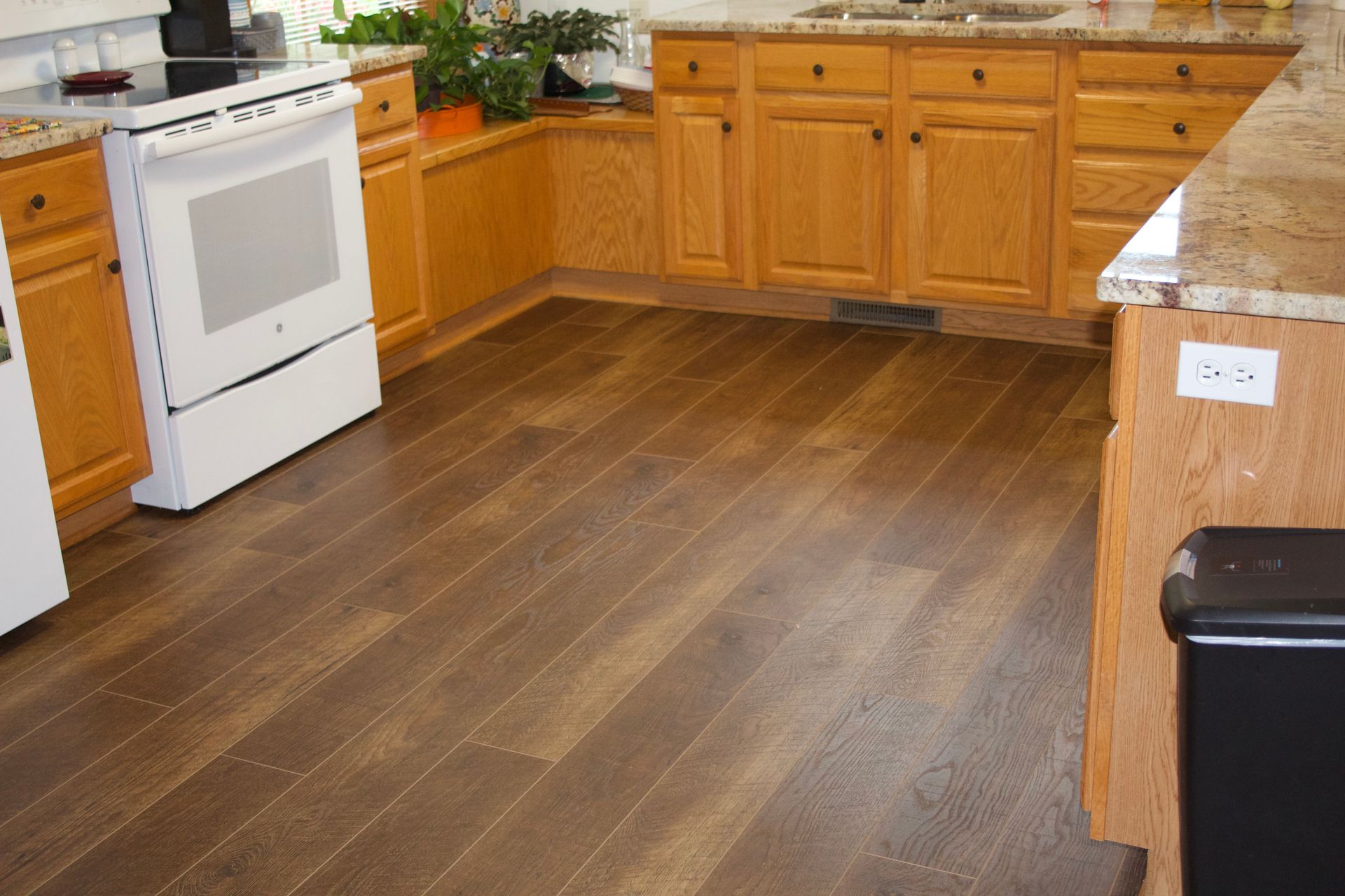 Kitchen with medium brown hardwood floors, light brown cabinets, and a white stove.
