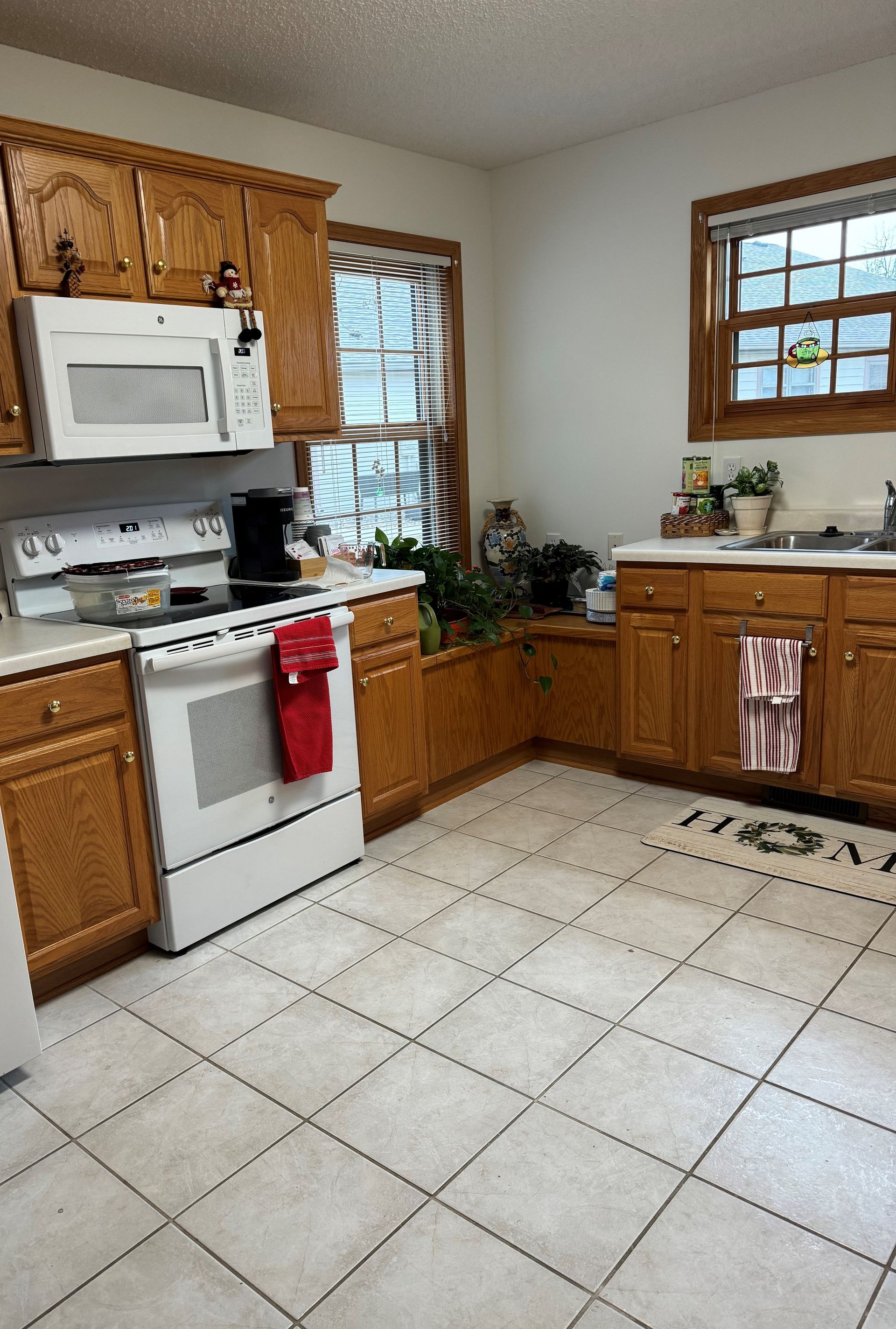 A kitchen with wooden cabinets, white appliances, and a window above the sink and countertop.