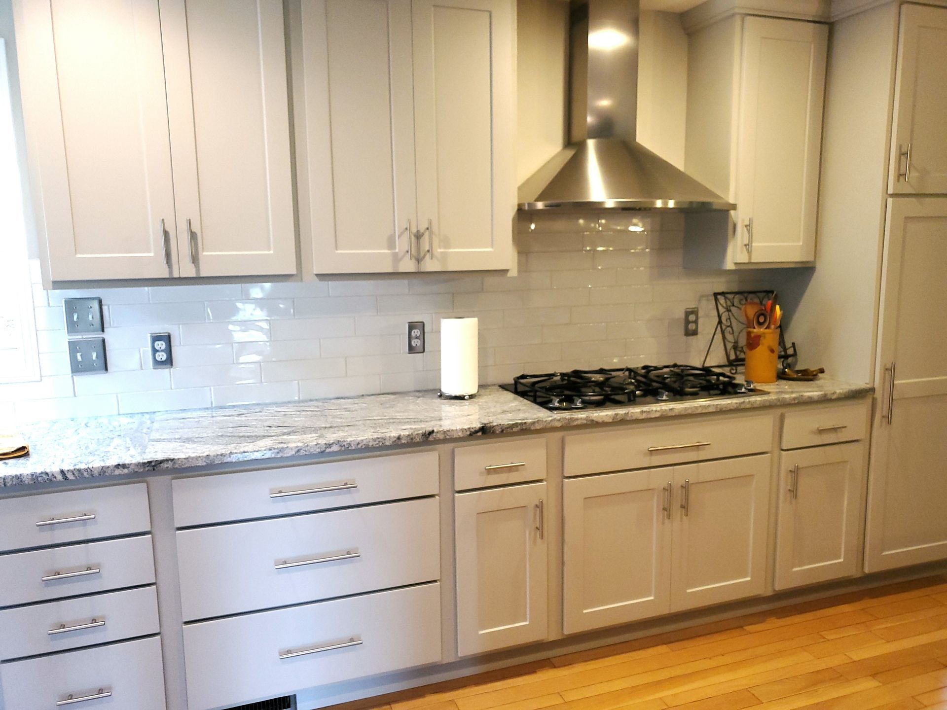 Light gray kitchen cabinets with silver hardware and granite countertops.