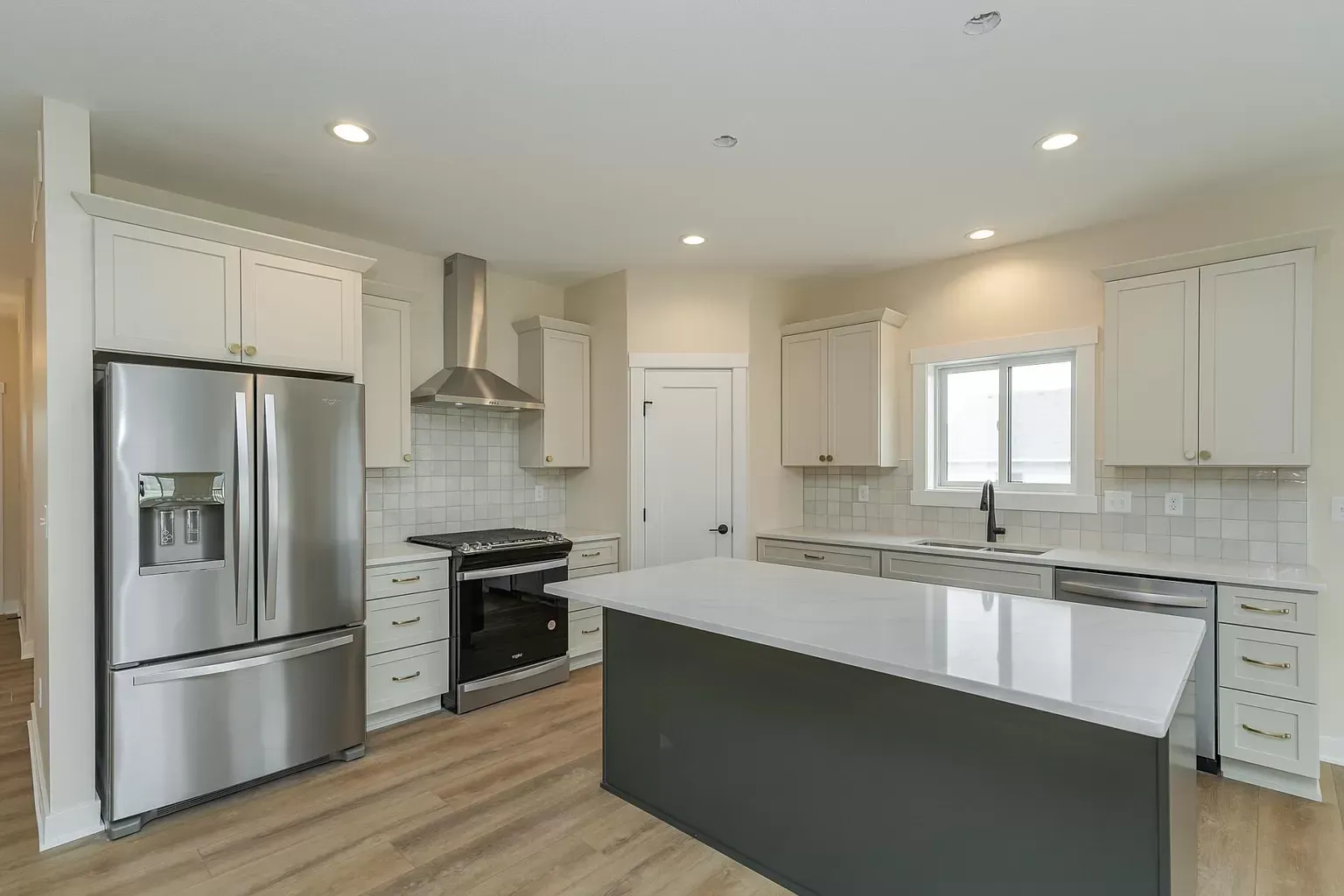 A kitchen with stainless steel appliances , white cabinets , and a large island.
