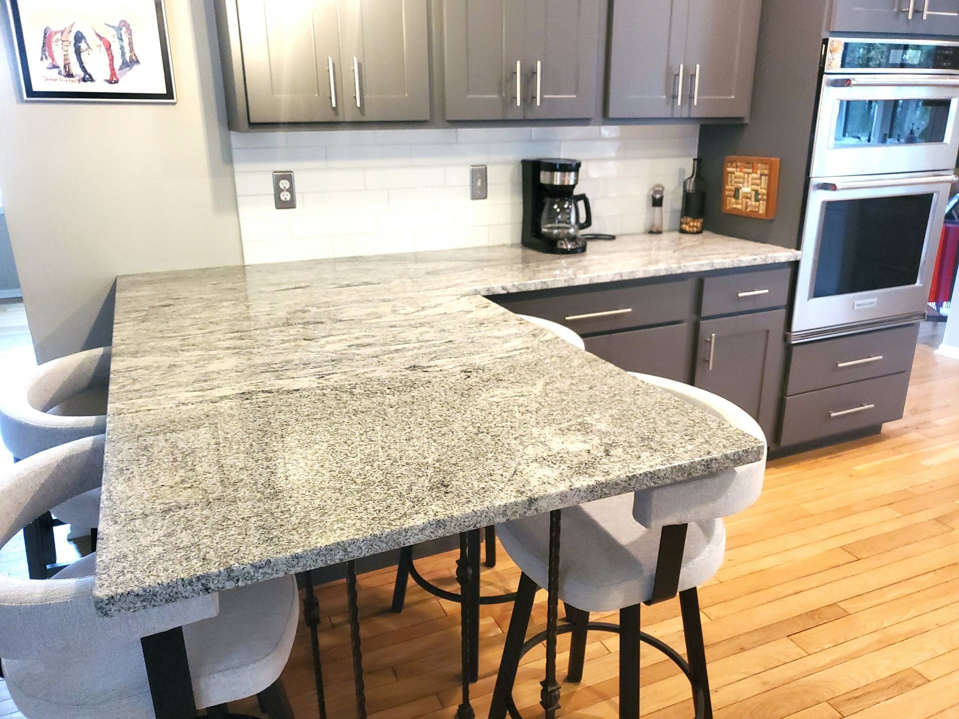Gray kitchen with granite countertops, gray cabinets, and bar stools.