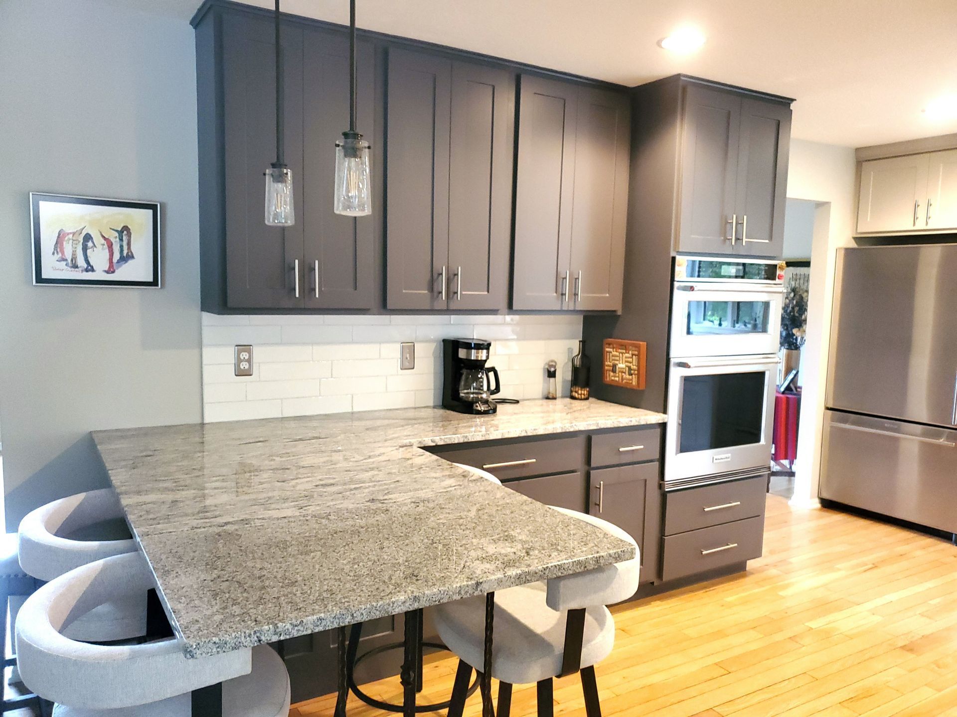 Modern gray kitchen with granite countertop, white subway tile, and stainless steel appliances.