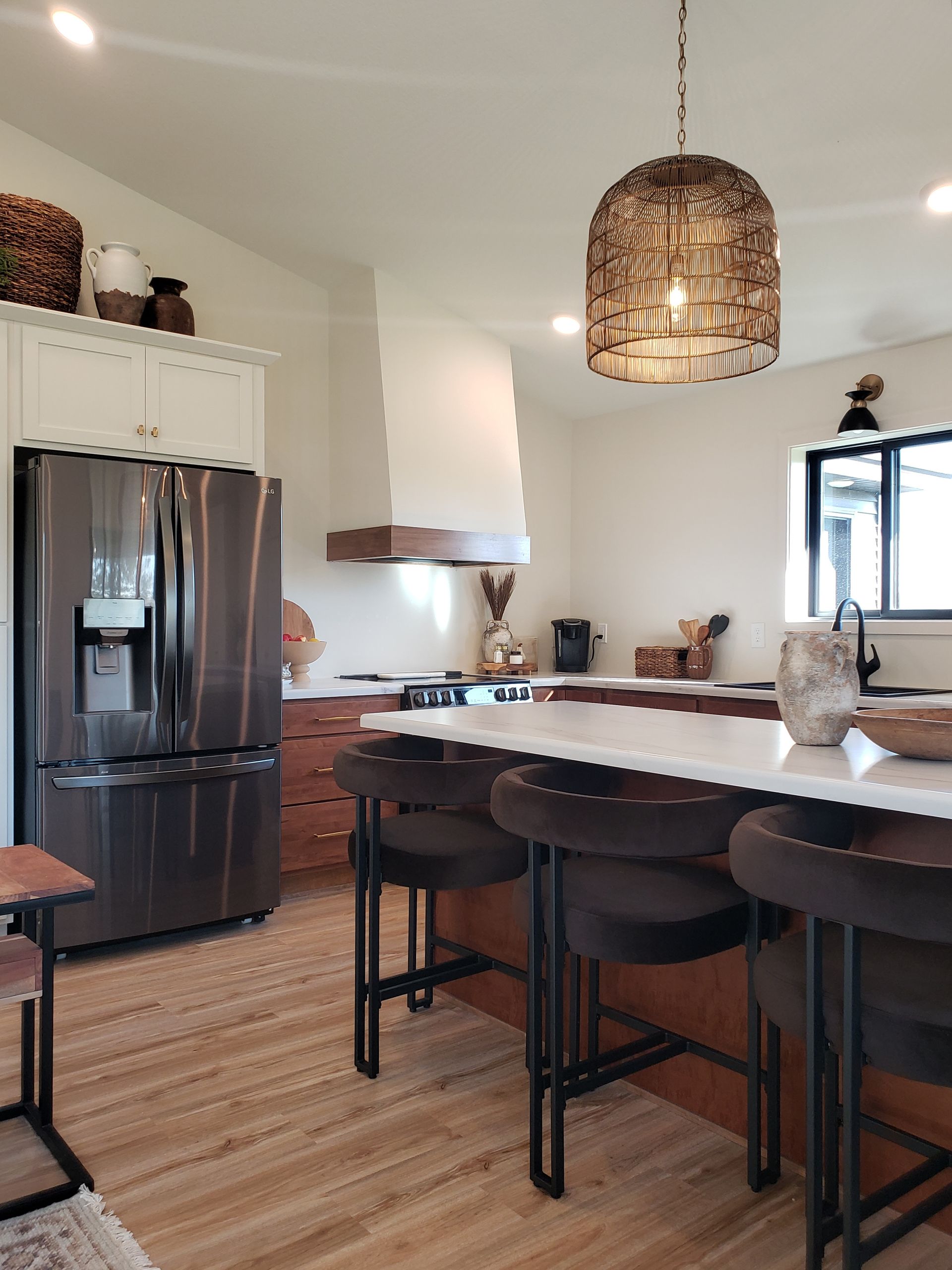Modern kitchen with dark appliances, island seating, pendant light, and wood accents.