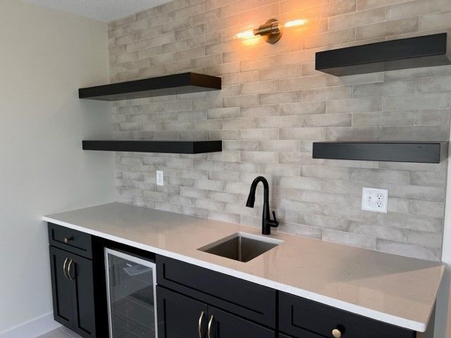 A kitchen with a sink , refrigerator and shelves
