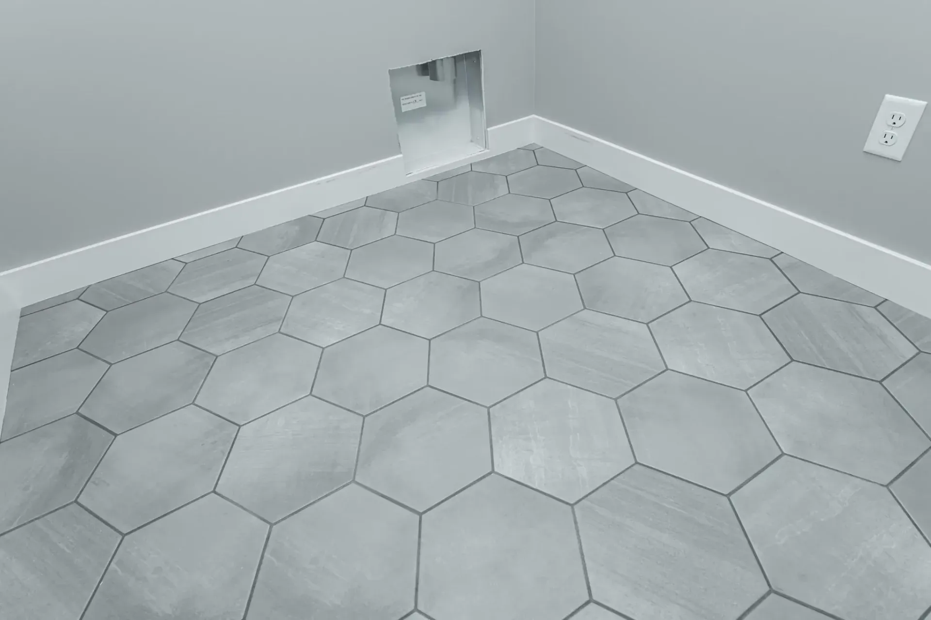 A room with a hexagonal tile floor and a hole in the wall.