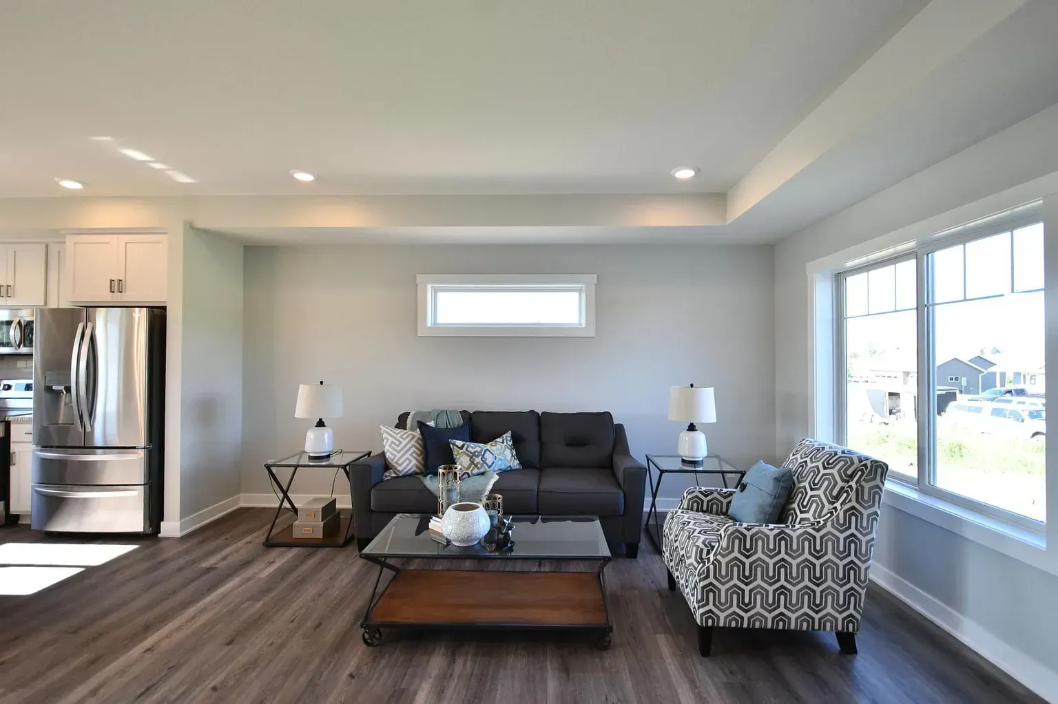 A living room with a couch , chair , coffee table , and refrigerator.