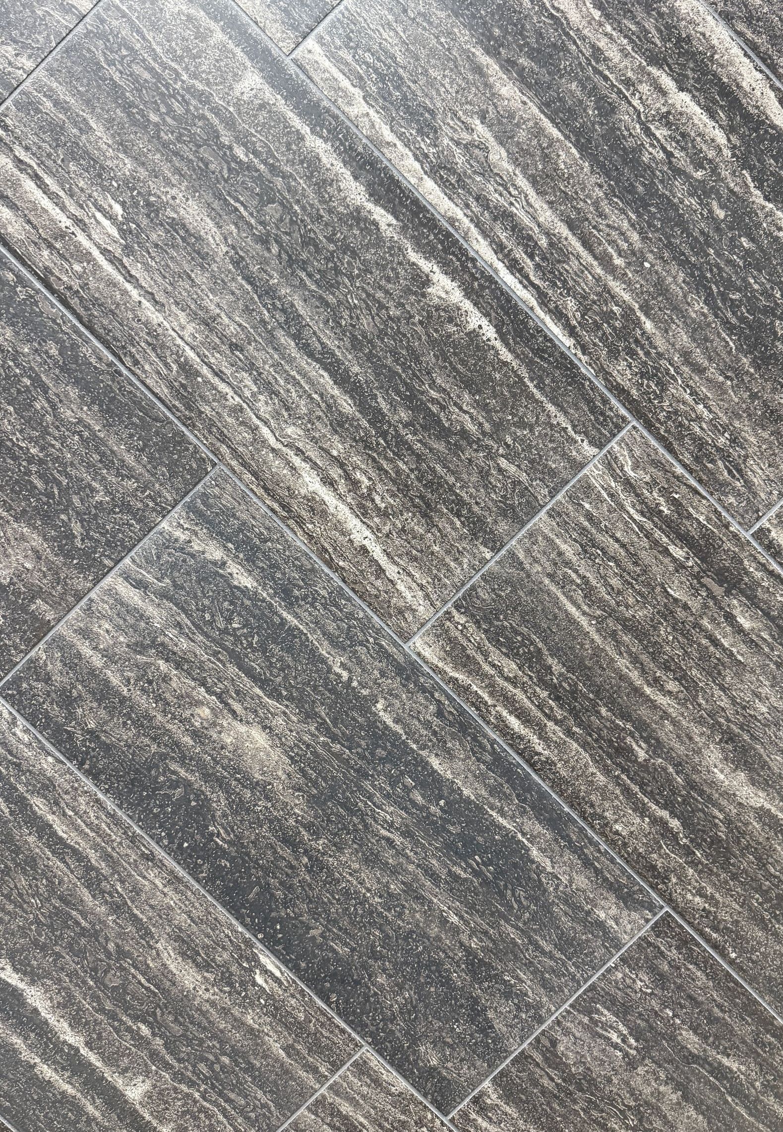 A close up of a black tile floor with a diagonal pattern.
