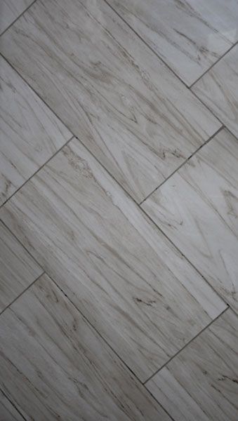 A close up of a tile floor that looks like wood.