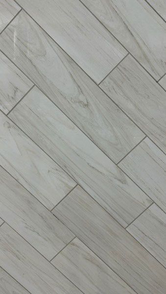 A close up of a white tile floor that looks like wood.