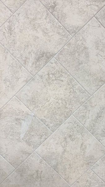 A close up of a white tile floor with a diamond pattern.