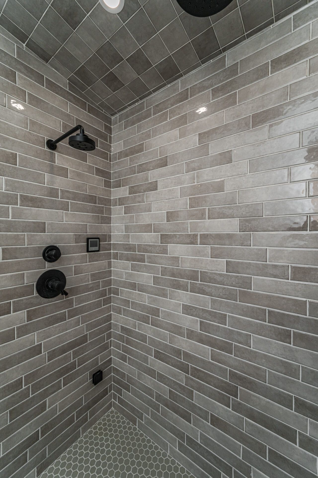 Gray tiled shower with black fixtures.