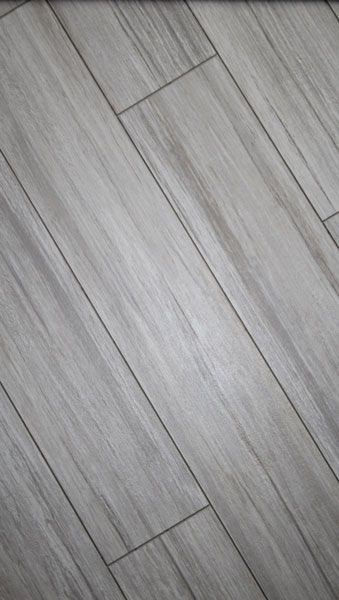 A close up of a gray tile floor that looks like wood.