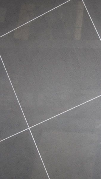 A close up of a gray tile floor with white lines.