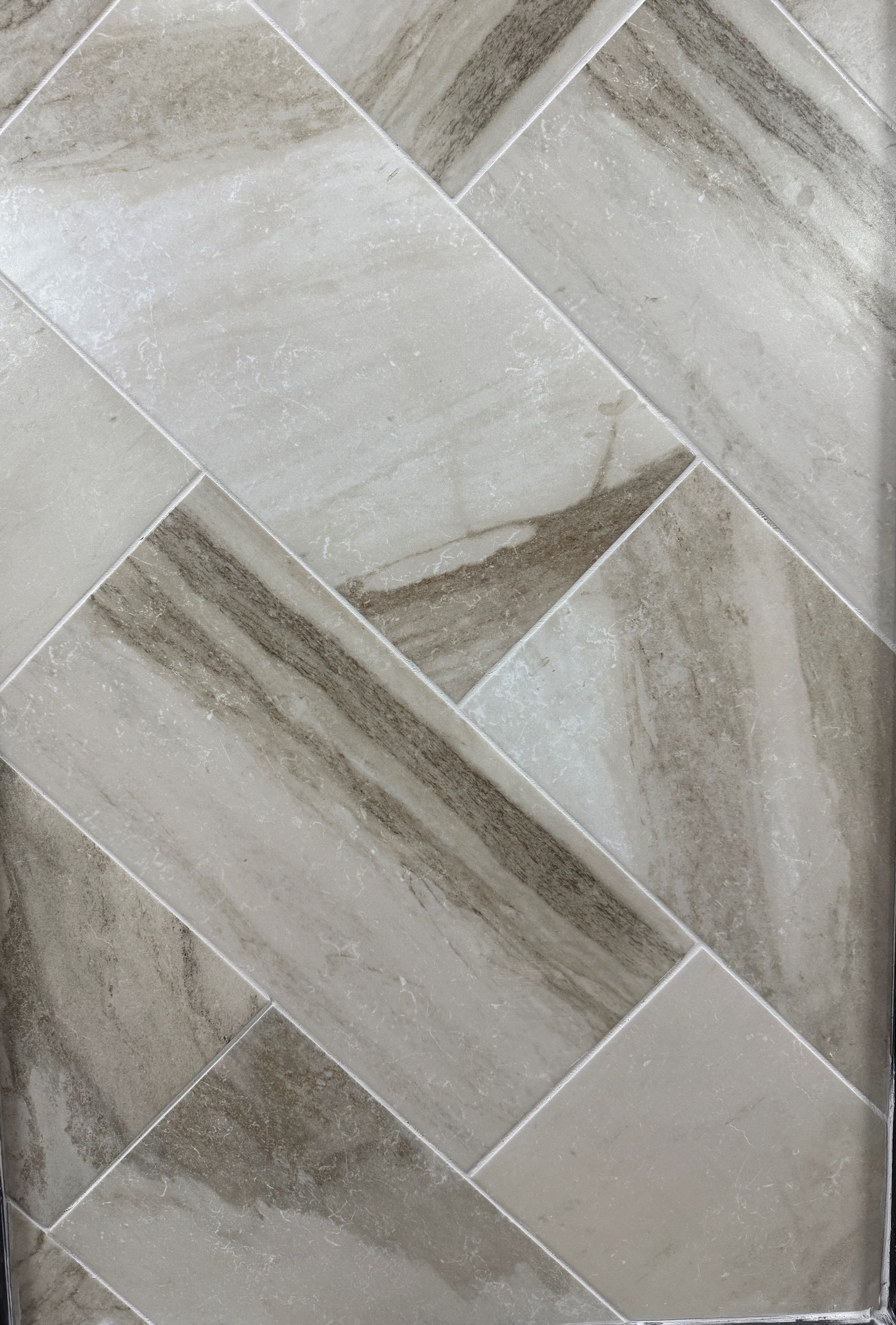 A close up of a tile floor with a herringbone pattern.