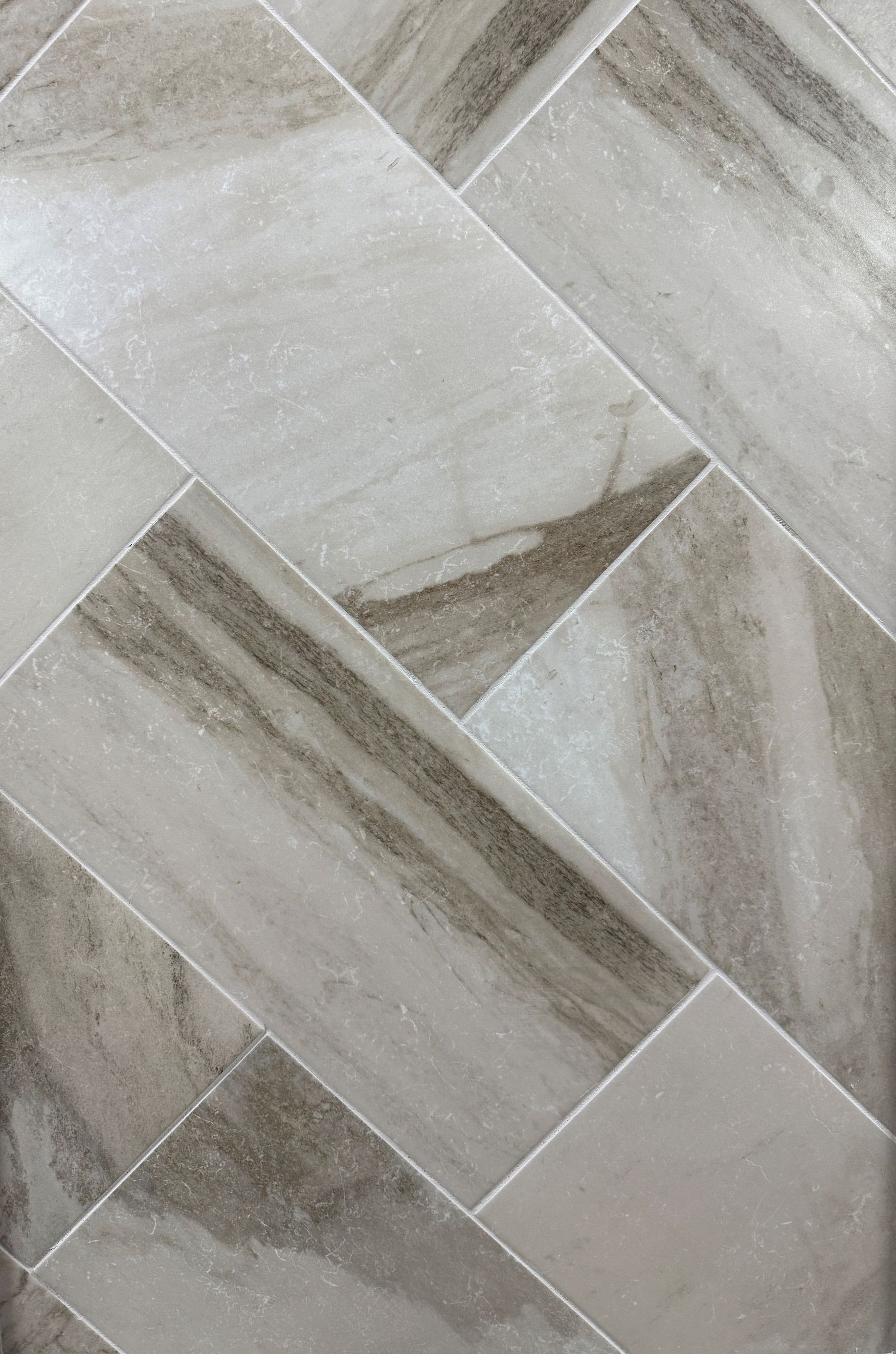 A close up of a tile floor with a herringbone pattern.