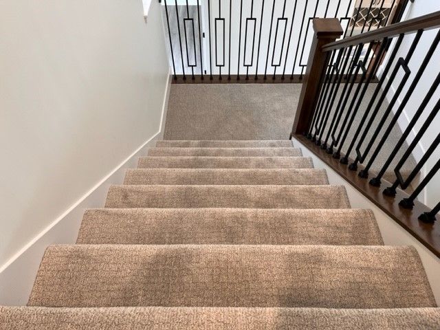 A staircase with a carpeted staircase and a metal railing.
