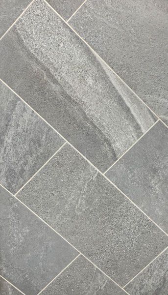 A close up of a gray tile floor with a white border.