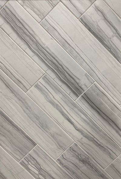 A close up of a white tile floor that looks like wood.