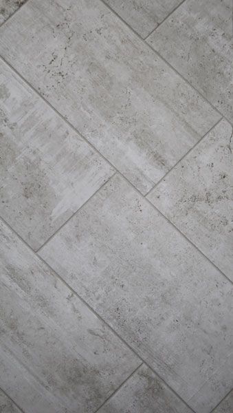 A close up of a gray tile floor with a diagonal pattern.