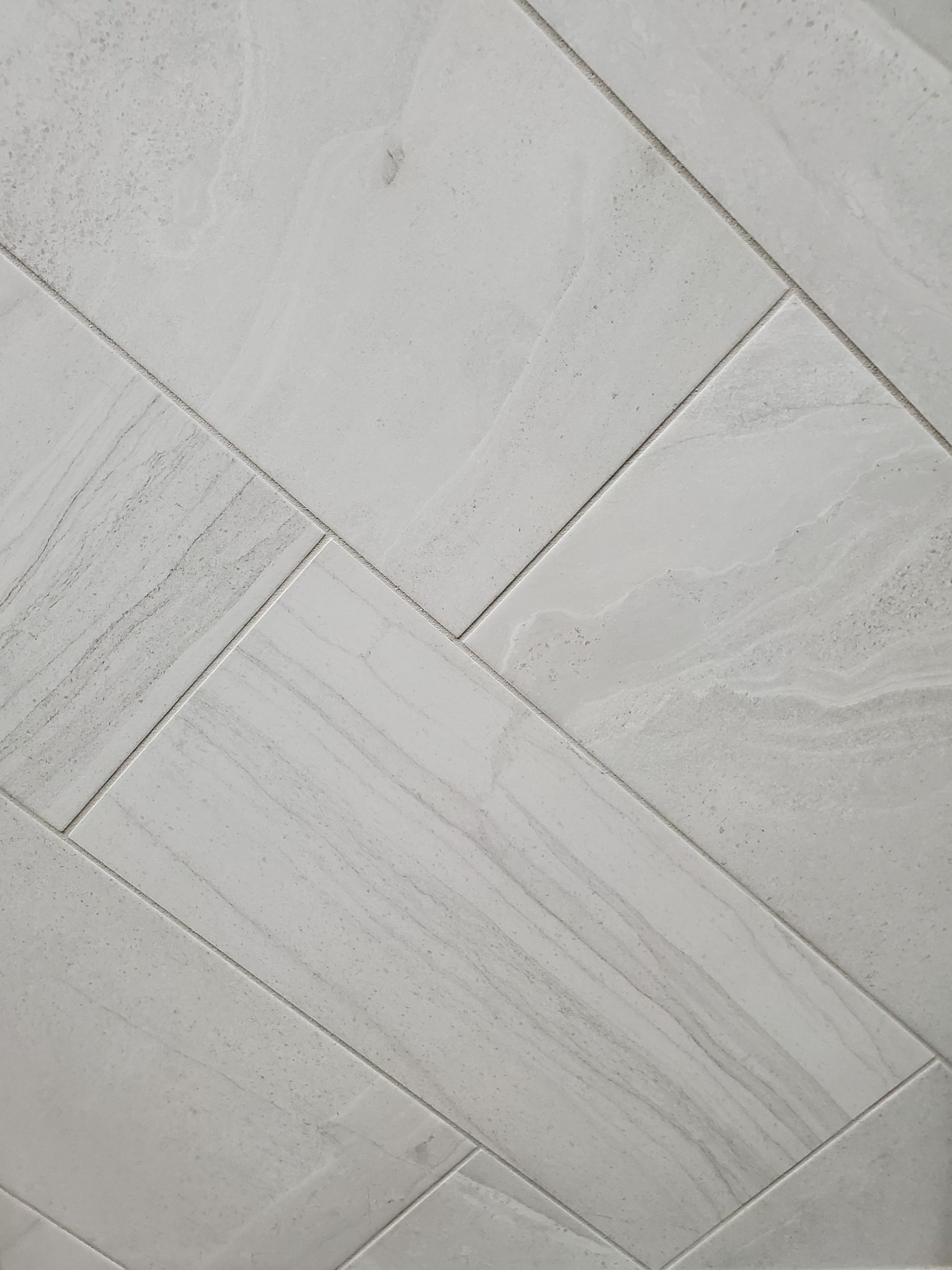 A close up of a white tile floor with a diagonal pattern.