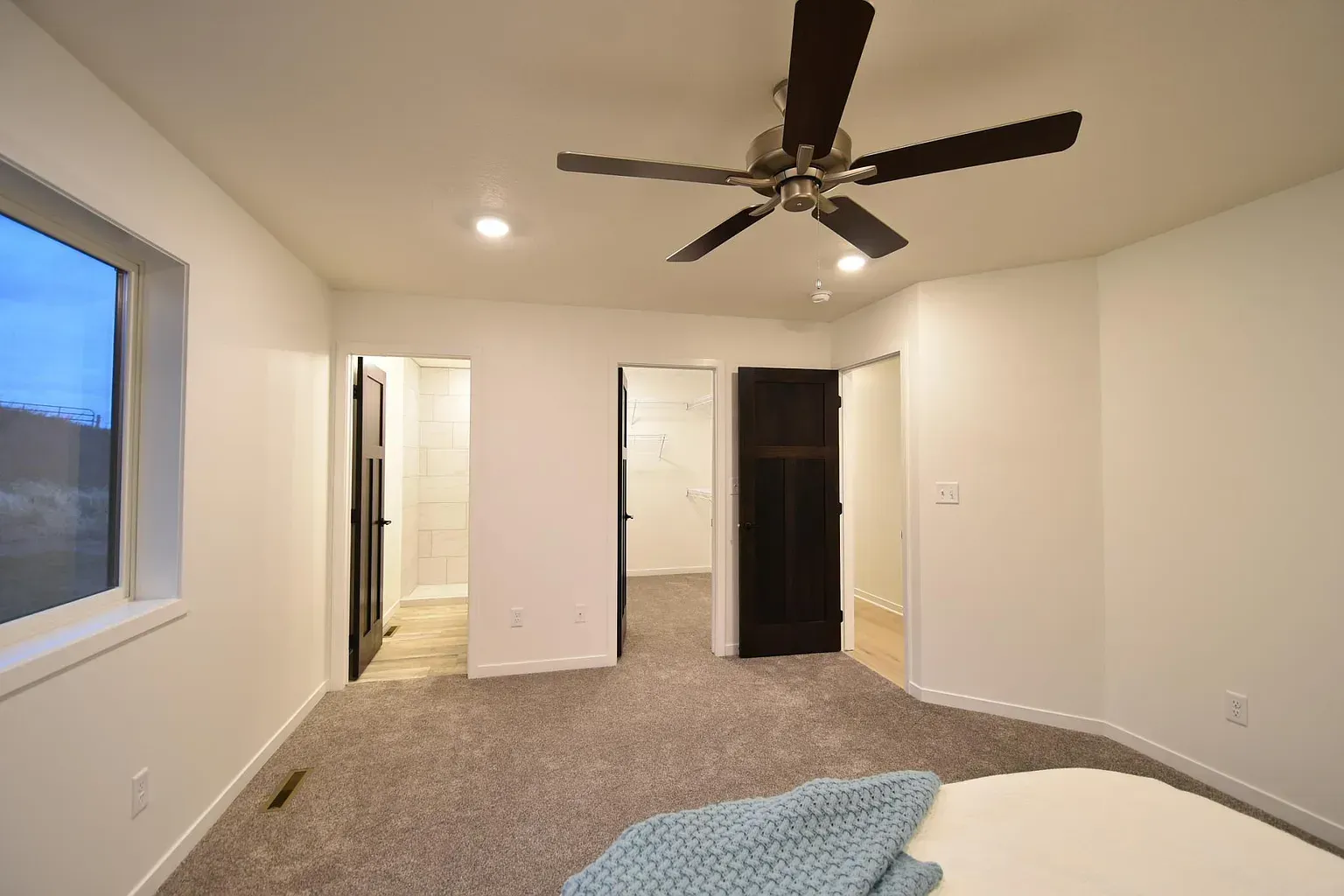 A bedroom with a bed and a ceiling fan.