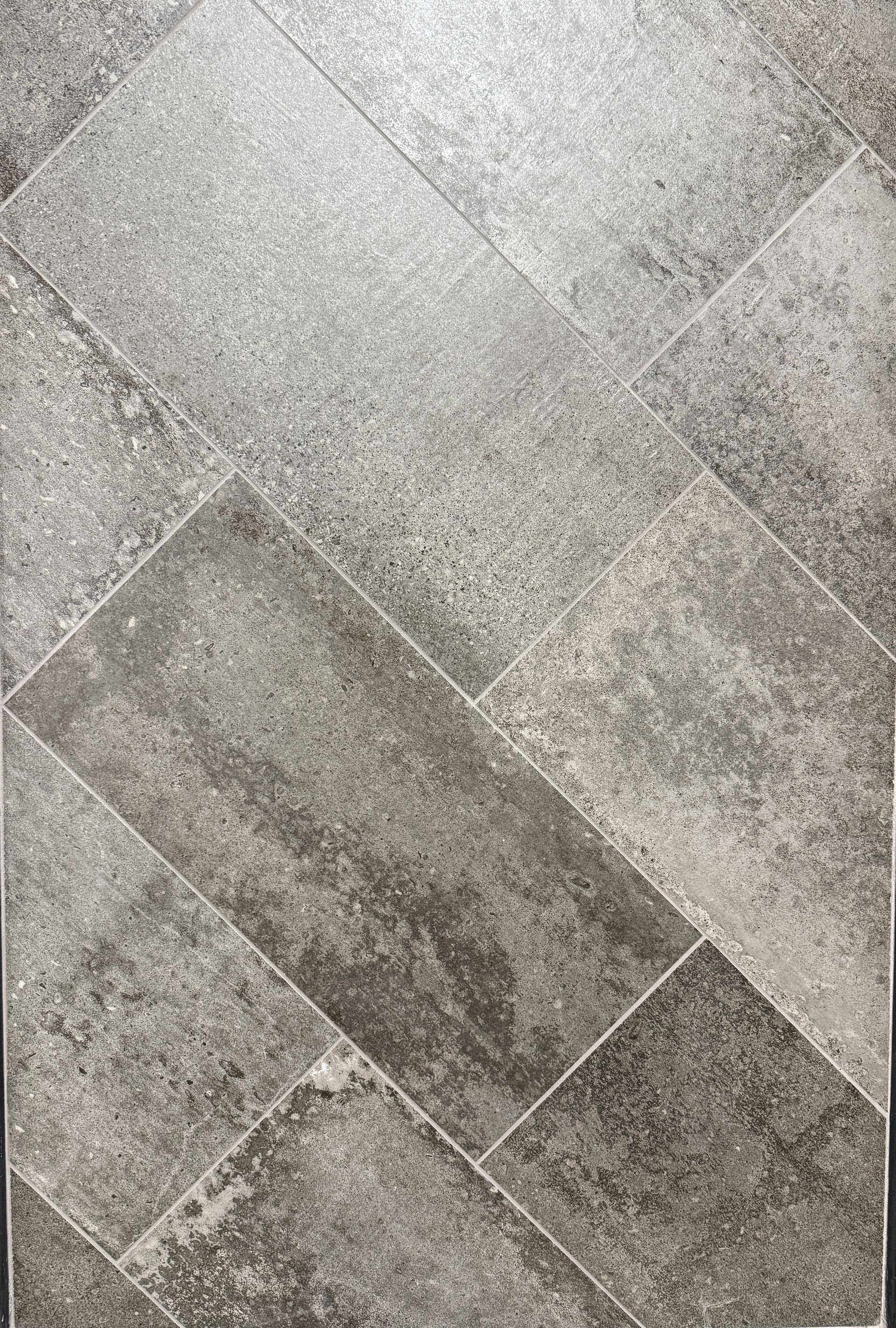 A close up of a gray tile floor with a diagonal pattern.