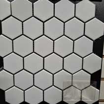 A close up of a white hexagon mosaic tile on a black surface.