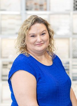 The woman is wearing a blue shirt and smiling for the camera.