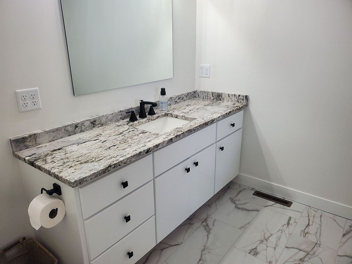 A bathroom with a sink , mirror , and marble floor.
