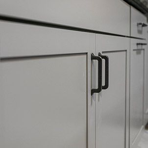 A close up of a kitchen cabinet with black handles.