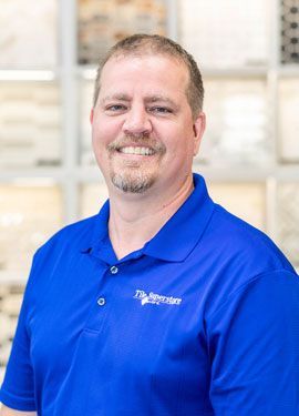 A man wearing a blue polo shirt is smiling for the camera.