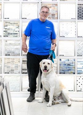 A man is standing next to a dog in a tile store.