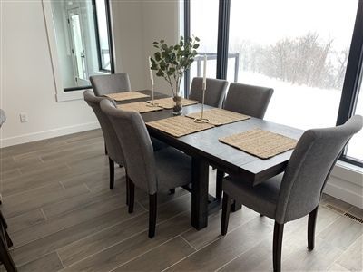 Dining room with gray table and chairs, place mats, and window view of snow.