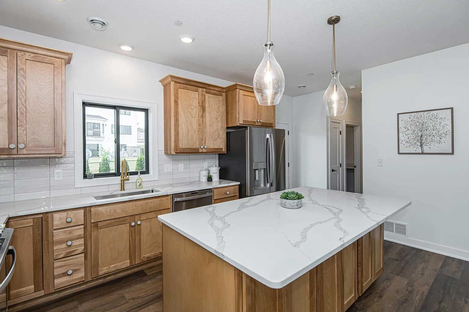 A kitchen with wooden cabinets and a large island in the middle.