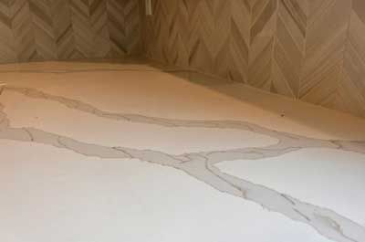 A bathroom with a white counter top and a wooden wall.