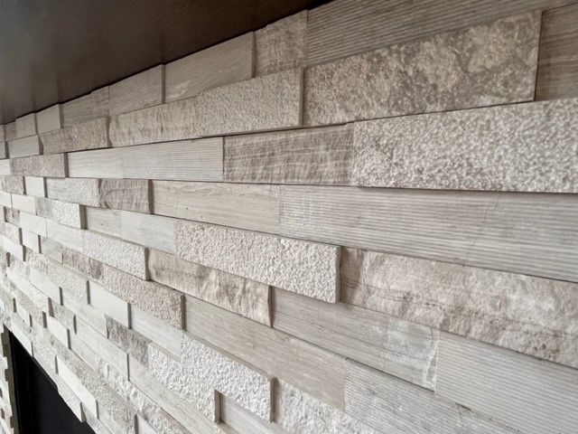 A fireplace with a brick wall and a wooden mantle.