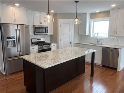Modern kitchen with white cabinets, stainless steel appliances, and dark island with granite countertop.