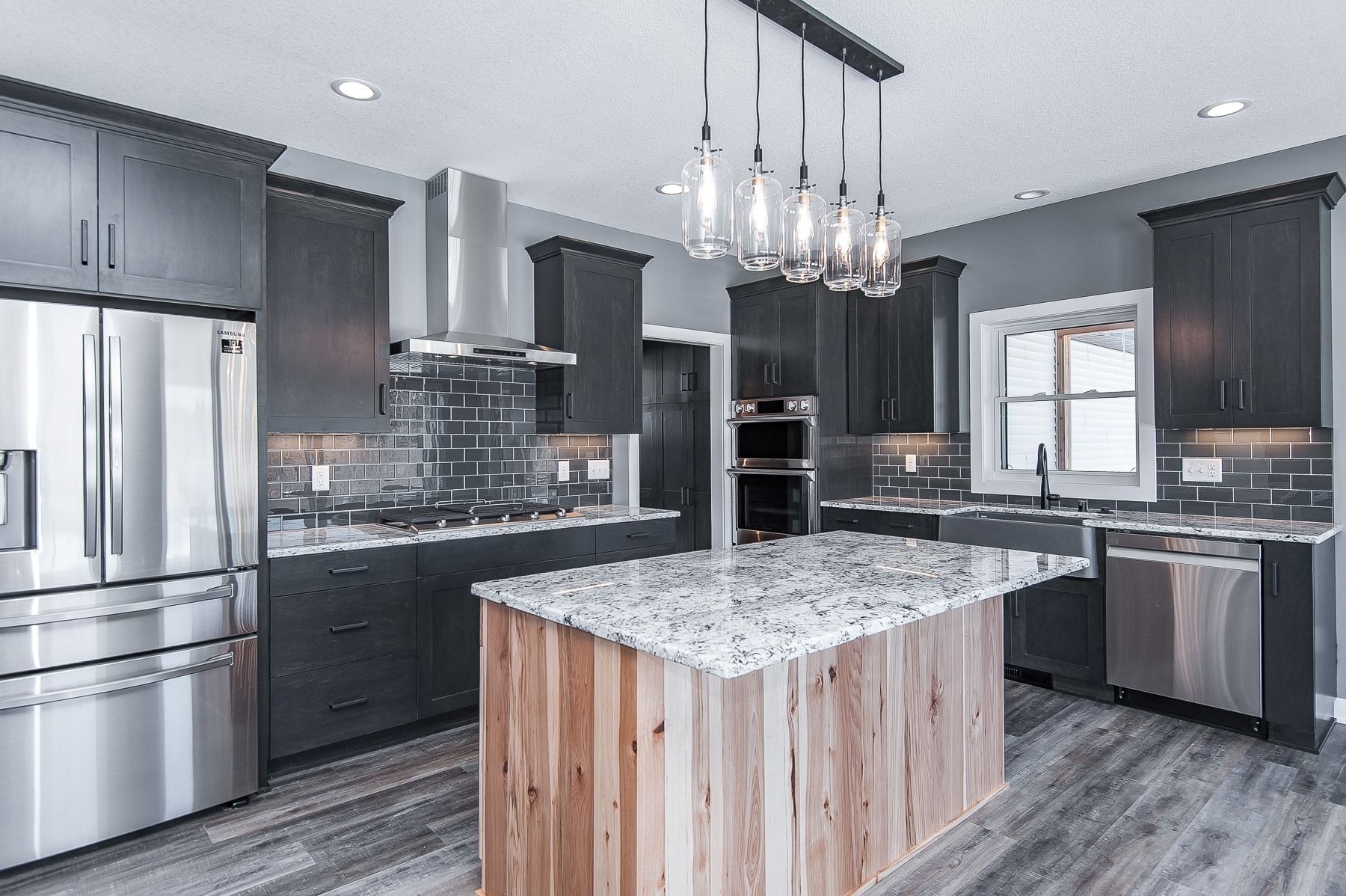 A kitchen with stainless steel appliances and a large island in the middle.