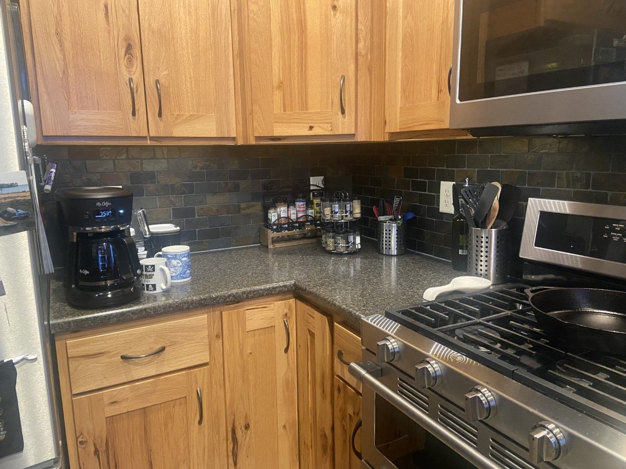 A kitchen with wooden cabinets , stainless steel appliances , a stove and a microwave.