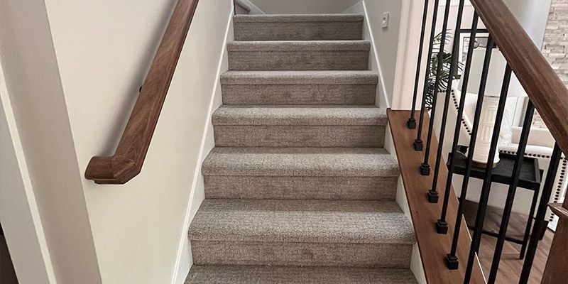 The stairs are carpeted and have a wooden railing.