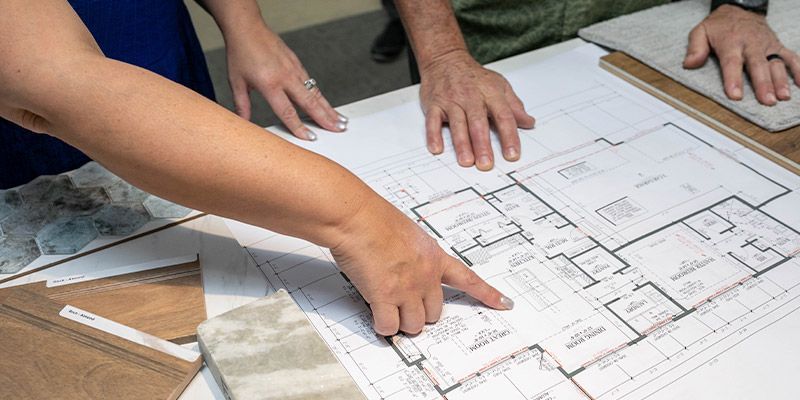 A man and a woman are looking at a floor plan of a house.