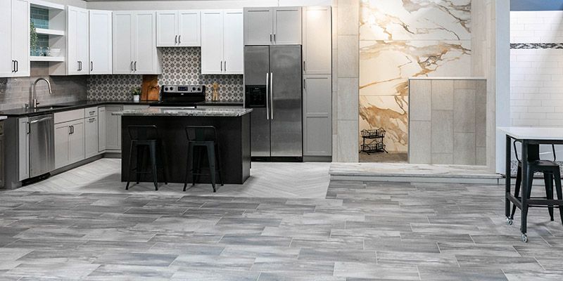 A kitchen with white cabinets , stainless steel appliances , and a large island.