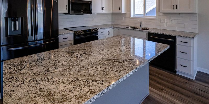 A kitchen with granite counter tops , black appliances , and white cabinets.