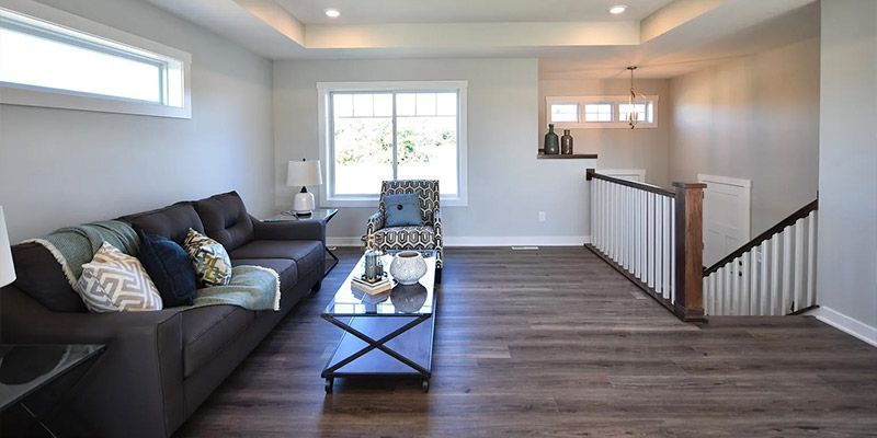 A living room with a couch , chair , coffee table and stairs.