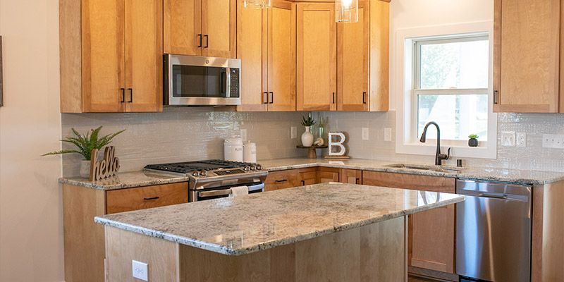 A kitchen with wooden cabinets , granite counter tops , stainless steel appliances and a large island.