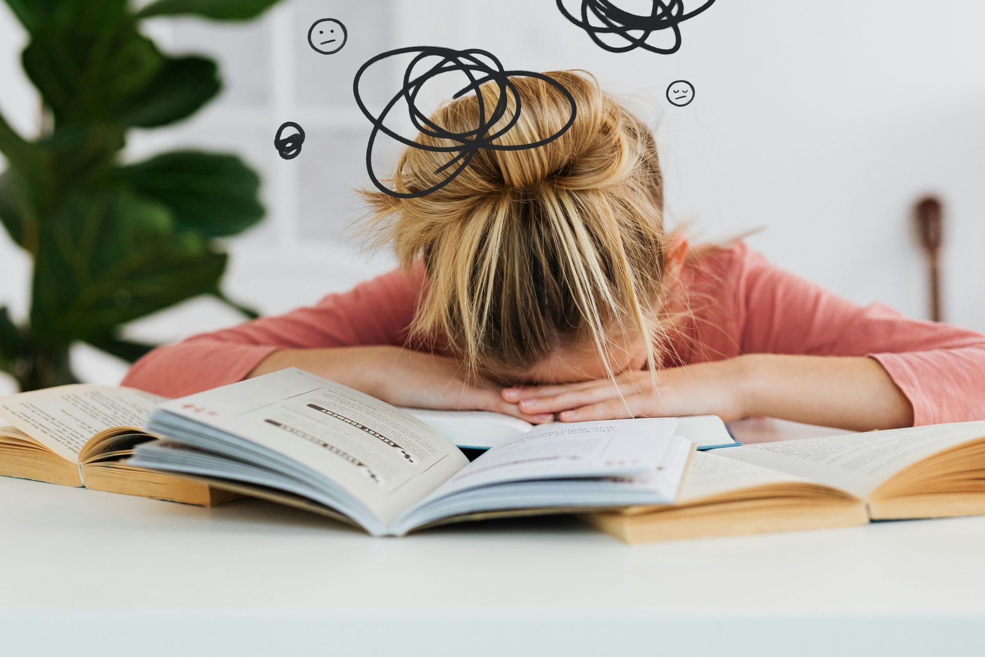 Woman resting head on desk, overwhelmed by open books, scribbled lines above her.