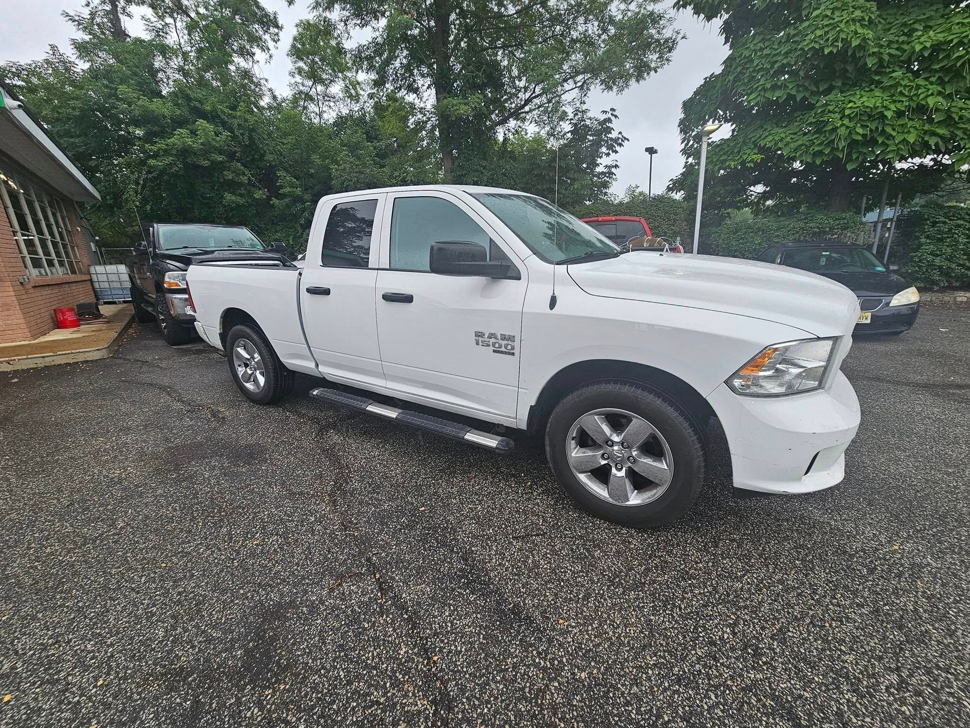 A white truck is parked in a gravel lot in front of a house.