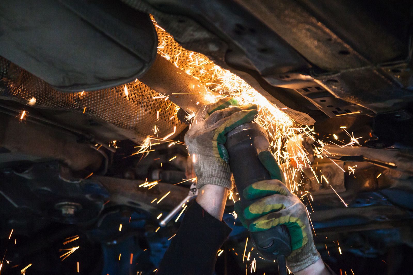 A man is grinding the exhaust pipe of a car.