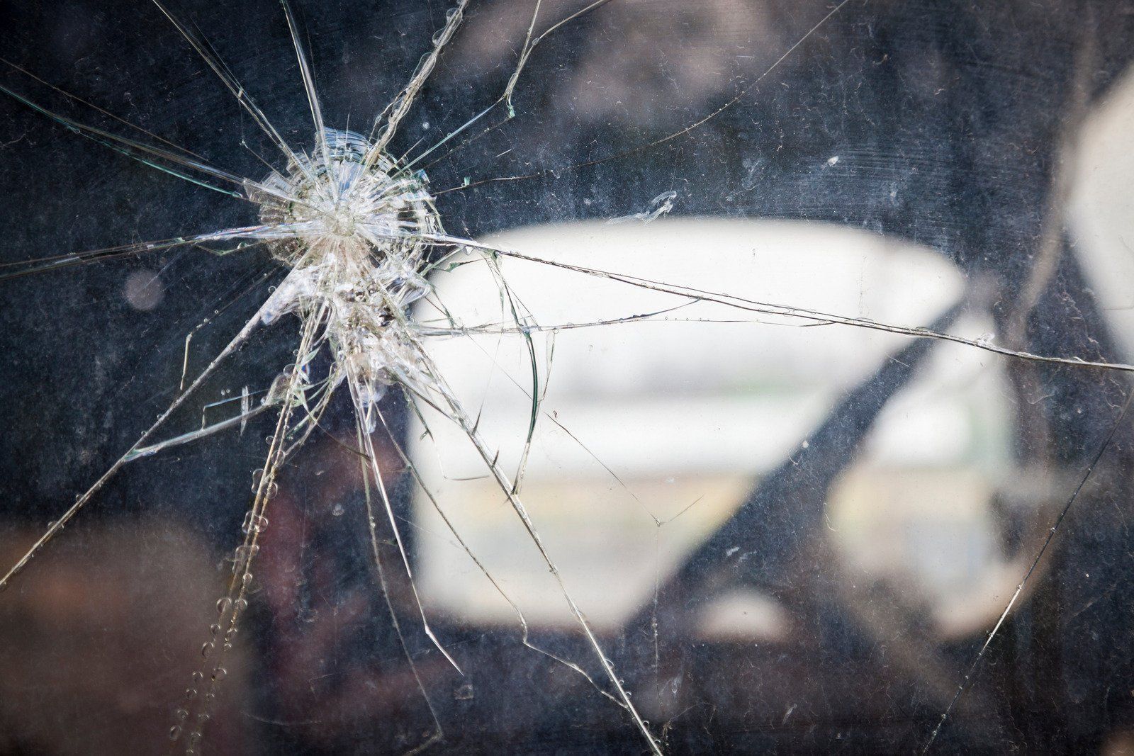 A close up of a broken glass window with a hole in it.